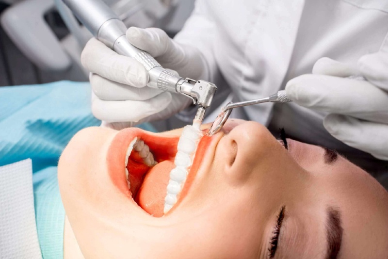 A dental hygienist performing a bi-annual teeth cleaning on patient in Parker, Colorado.