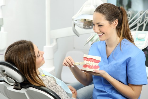 A dentist teaches a patient the proper way to clean their teeth